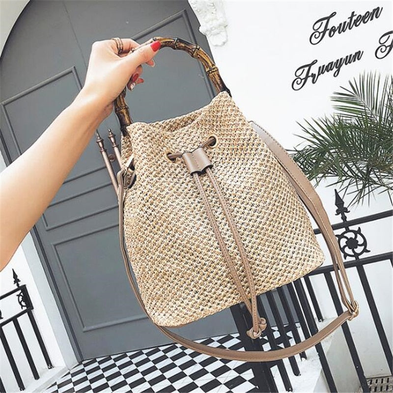 foto de mão de mulher segurando bolsa de palha feminina collen na alça de mão